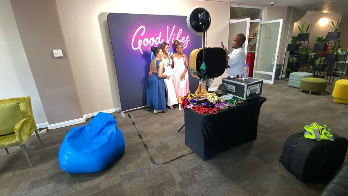 Guests posing at a Selfie Cube booth with a Good Vibes backdrop
