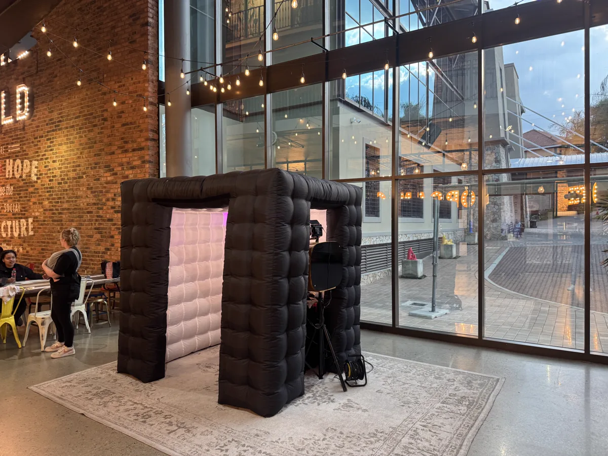 Black inflatable photo booth set up in a modern glass venue