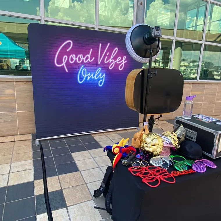 Selfie Cube photo booth with a Good Vibes event backdrop and props
